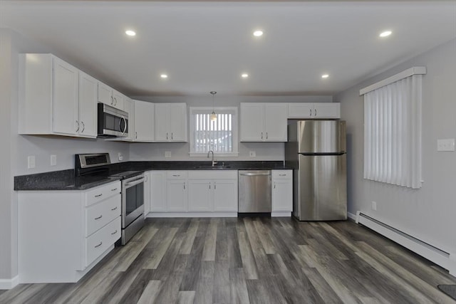 kitchen featuring white cabinets, dark countertops, stainless steel appliances, a baseboard heating unit, and a sink