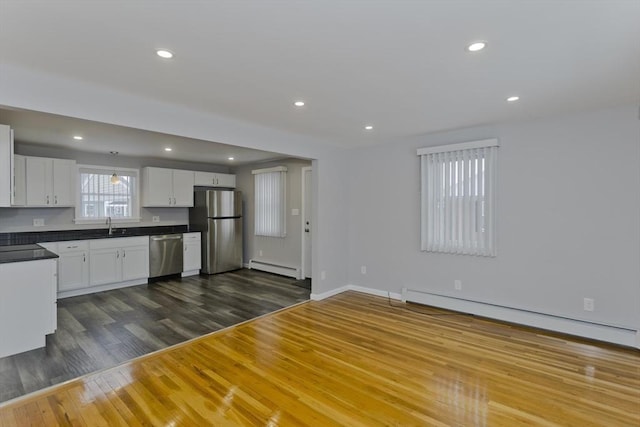 kitchen with stainless steel appliances, dark wood-style flooring, white cabinets, and baseboard heating