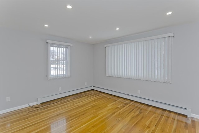 unfurnished room featuring a baseboard heating unit, baseboards, wood finished floors, and recessed lighting