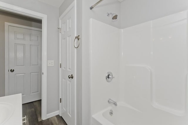 bathroom featuring shower / tub combination, baseboards, wood finished floors, and vanity