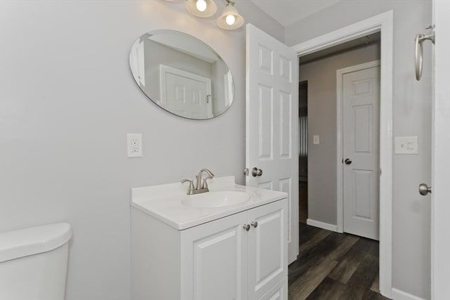 bathroom featuring baseboards, vanity, toilet, and wood finished floors