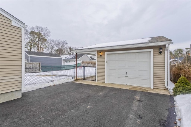 garage featuring aphalt driveway and fence