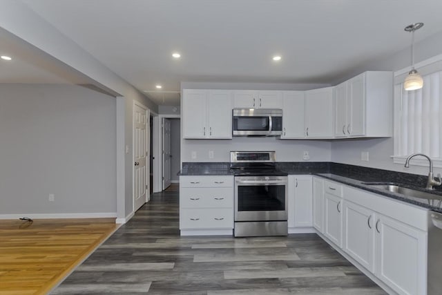 kitchen featuring recessed lighting, stainless steel appliances, a sink, white cabinets, and dark wood finished floors