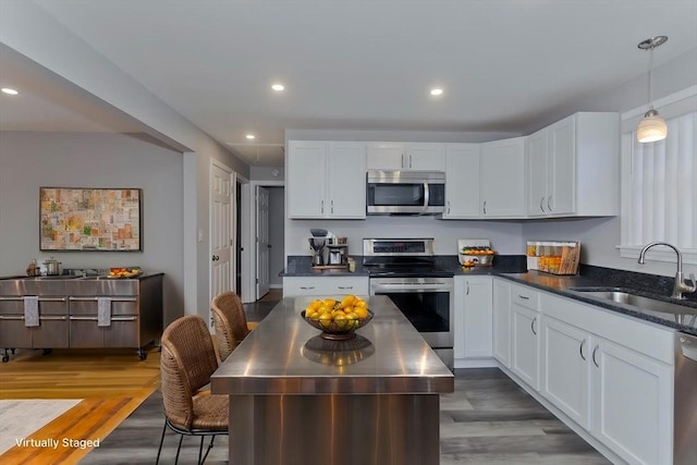 kitchen with white cabinets, wood finished floors, stainless steel appliances, a sink, and recessed lighting