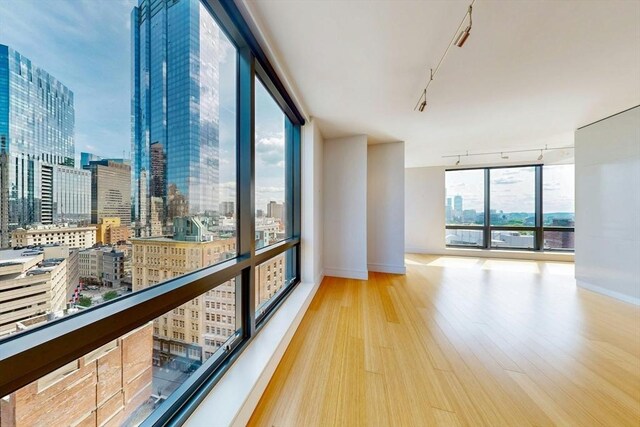 45 Province St Unit U1602, Boston, MA 02108 - unfurnished room featuring track lighting, a view of city, wood finished floors, and baseboards