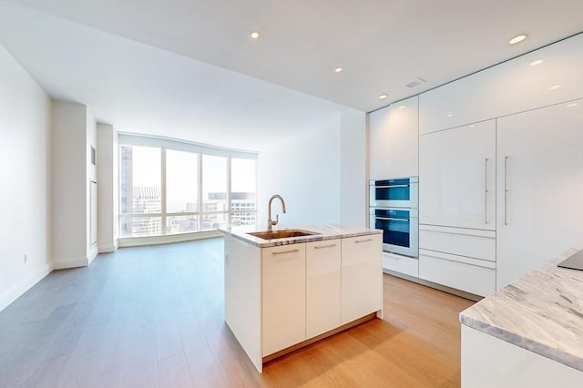 kitchen featuring sink, white cabinets, floor to ceiling windows, and double oven