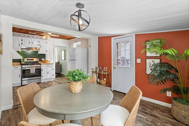 dining area with a notable chandelier, dark wood-type flooring, a wealth of natural light, and baseboards