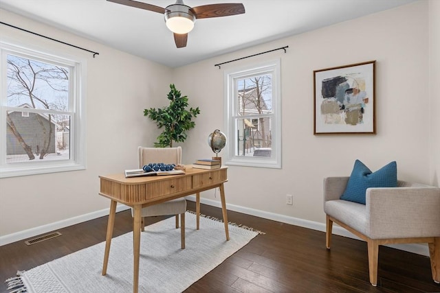 home office with a ceiling fan, dark wood-style flooring, visible vents, and baseboards