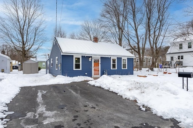 bungalow-style home featuring entry steps, an outdoor structure, a chimney, and a storage shed