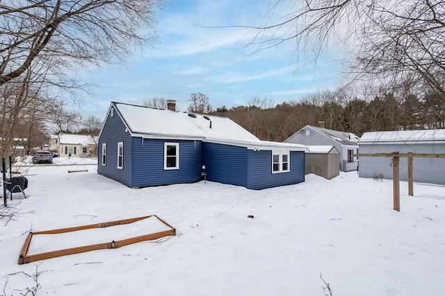 snow covered house featuring a chimney