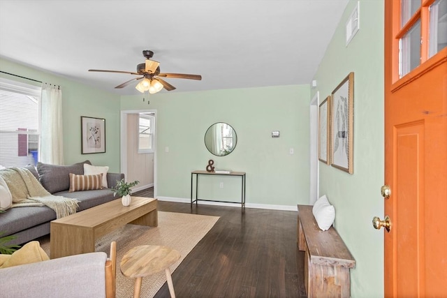 living area with visible vents, baseboards, dark wood finished floors, and a ceiling fan