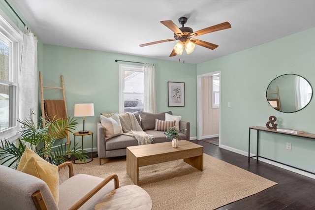 living area featuring dark wood-style floors, baseboards, and a ceiling fan