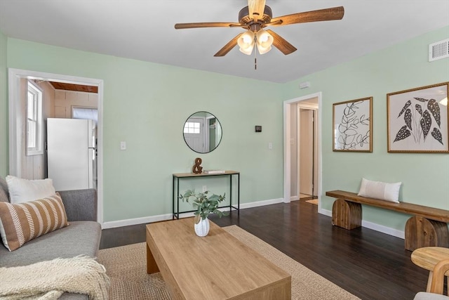 living area featuring visible vents, dark wood finished floors, a ceiling fan, and baseboards