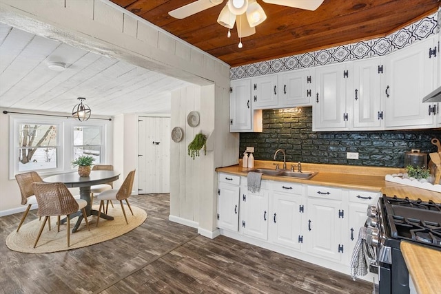 kitchen featuring white cabinetry, a sink, gas range, butcher block countertops, and wooden ceiling