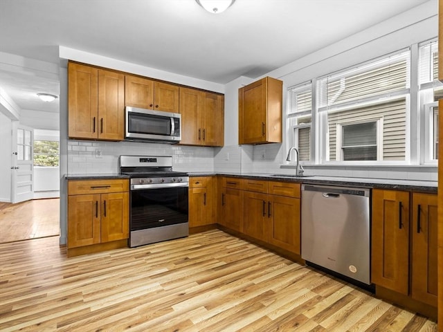 9-11 Edmunds St, Cambridge, MA 02140 - kitchen with stainless steel appliances, a sink, brown cabinets, light wood-style flooring, and dark countertops