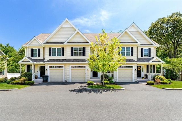 view of front of house featuring driveway, an attached garage, covered porch, and a shingled roof