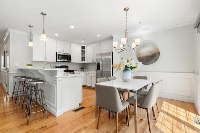 kitchen featuring stainless steel appliances, a peninsula, crown molding, glass insert cabinets, and a chandelier