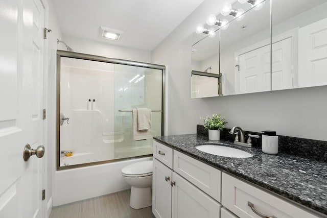 bathroom featuring vanity, toilet, and bath / shower combo with glass door