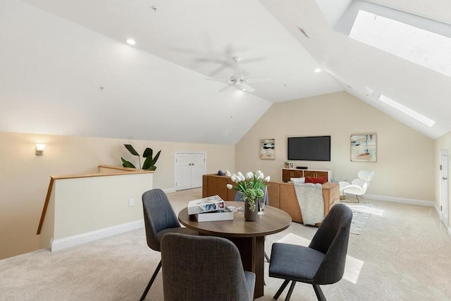 dining area with light carpet, a skylight, lofted ceiling, baseboards, and ceiling fan