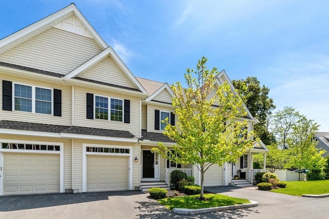 view of property with driveway, a shingled roof, and a garage