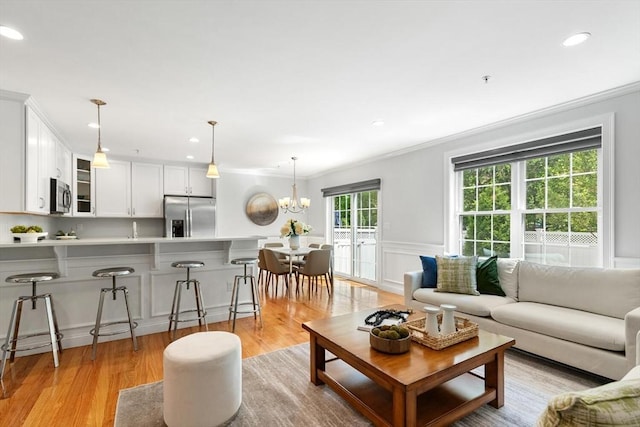 living room featuring ornamental molding, light wood-style flooring, recessed lighting, a chandelier, and wainscoting