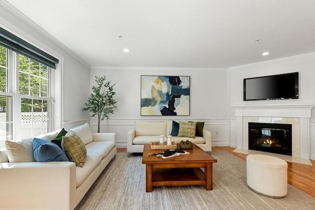 living area with wood finished floors, crown molding, recessed lighting, a fireplace with flush hearth, and a decorative wall