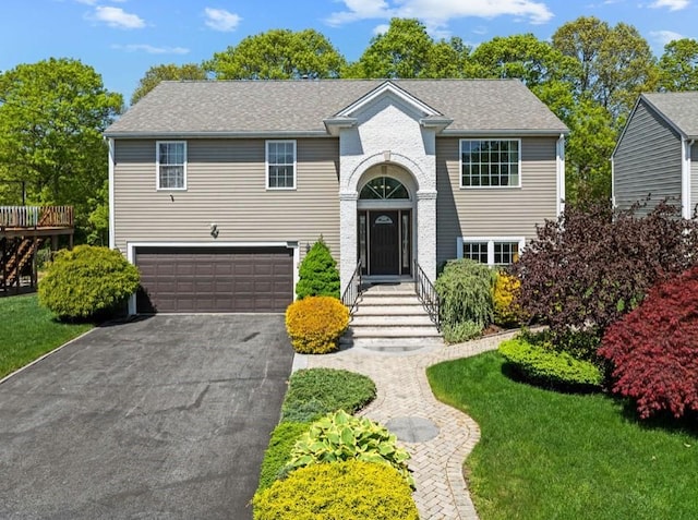 view of front of house featuring asphalt driveway, an attached garage, and a front yard