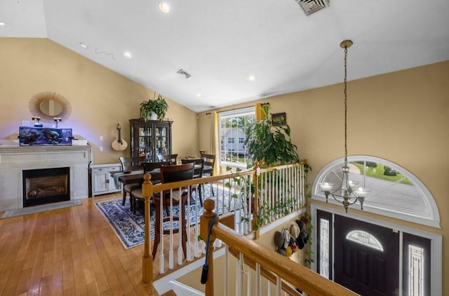 entrance foyer with a chandelier, lofted ceiling, a fireplace, wood-type flooring, and recessed lighting