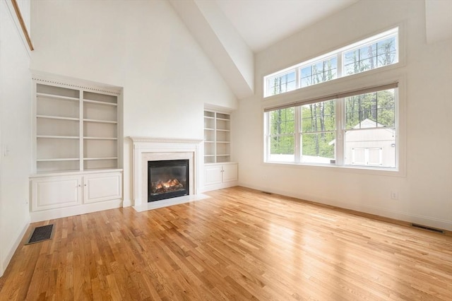 14 Chandler Ln, Amherst, NH 03031 - unfurnished living room featuring a high ceiling, wood finished floors, a fireplace with flush hearth, and built in shelves