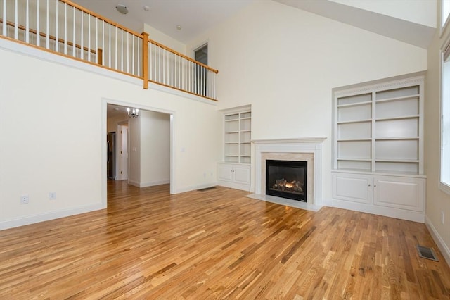 14 Chandler Ln, Amherst, NH 03031 - unfurnished living room with high vaulted ceiling, a fireplace, and light wood-style flooring