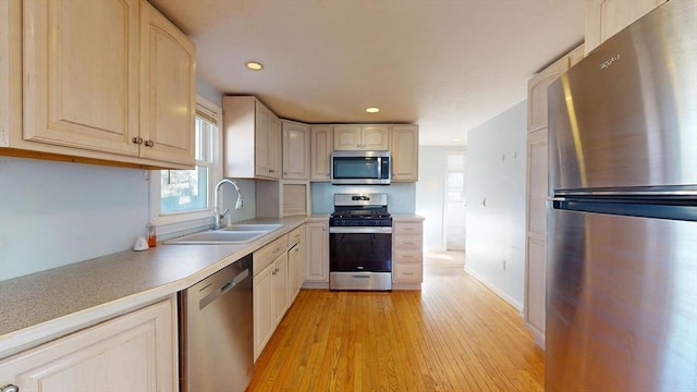 kitchen with light wood finished floors, recessed lighting, light countertops, appliances with stainless steel finishes, and a sink