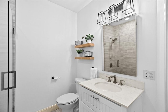 bathroom featuring a stall shower, toilet, vanity, and baseboards