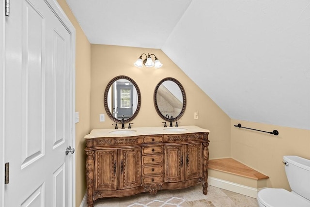 bathroom featuring lofted ceiling, toilet, baseboards, double vanity, and tile patterned flooring