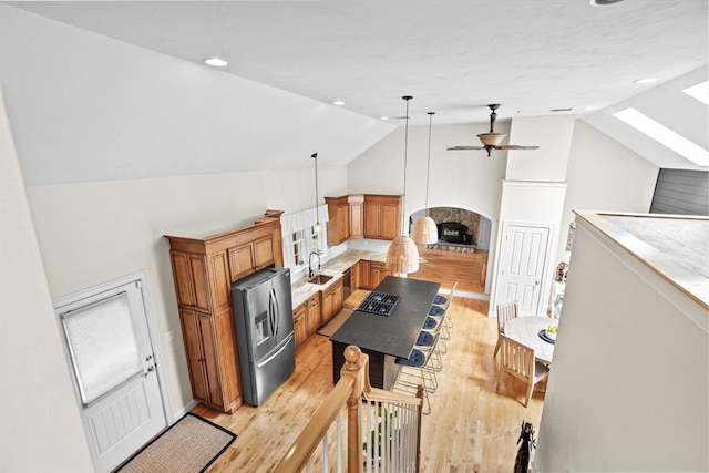 kitchen with stainless steel appliances, vaulted ceiling, light wood finished floors, ceiling fan, and a sink
