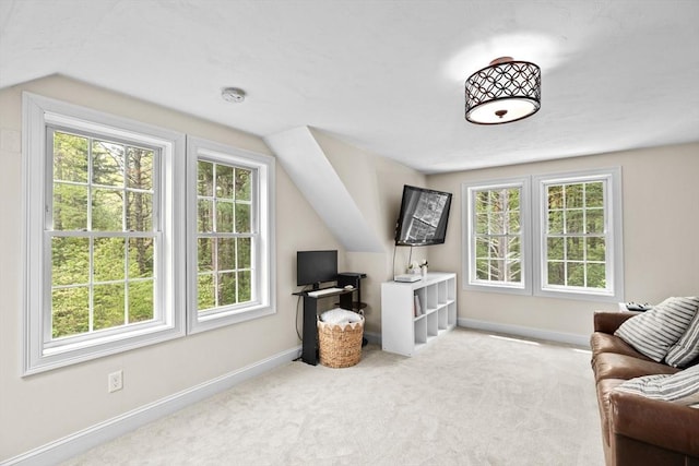 carpeted living area with healthy amount of natural light, baseboards, and vaulted ceiling