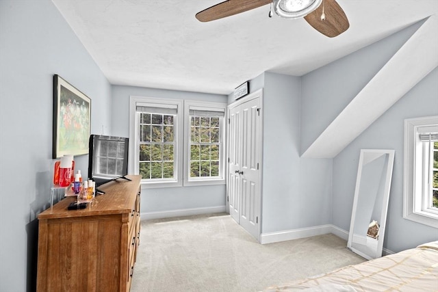 bedroom featuring light carpet, baseboards, multiple windows, and ceiling fan