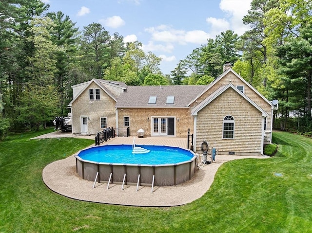 back of house featuring french doors, an outdoor pool, a lawn, and a chimney
