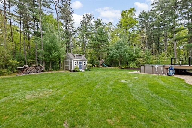 view of grassy yard with an outdoor pool, an outdoor structure, a playground, and a wooden deck