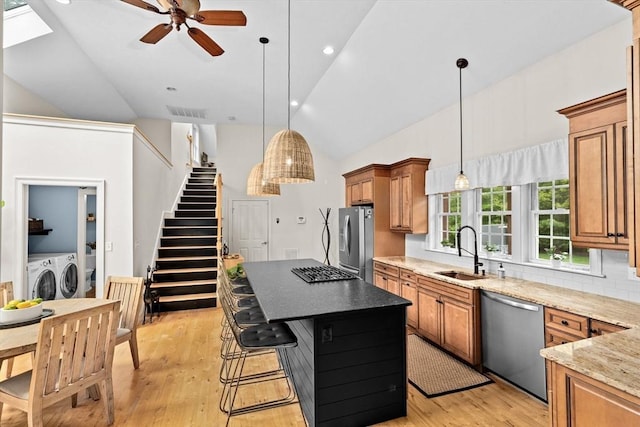 kitchen with appliances with stainless steel finishes, a sink, vaulted ceiling, separate washer and dryer, and ceiling fan
