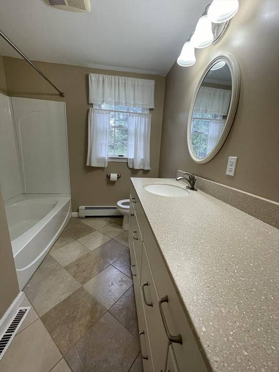 full bathroom featuring baseboard heating, vanity, baseboards, toilet, and shower / bathtub combination