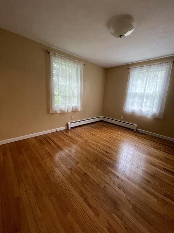 spare room featuring wood finished floors, a baseboard radiator, and baseboards