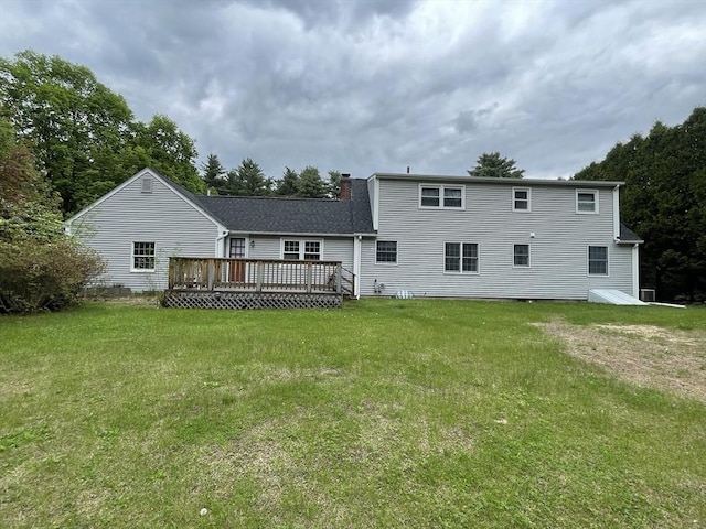 back of house featuring a deck, a lawn, and a chimney