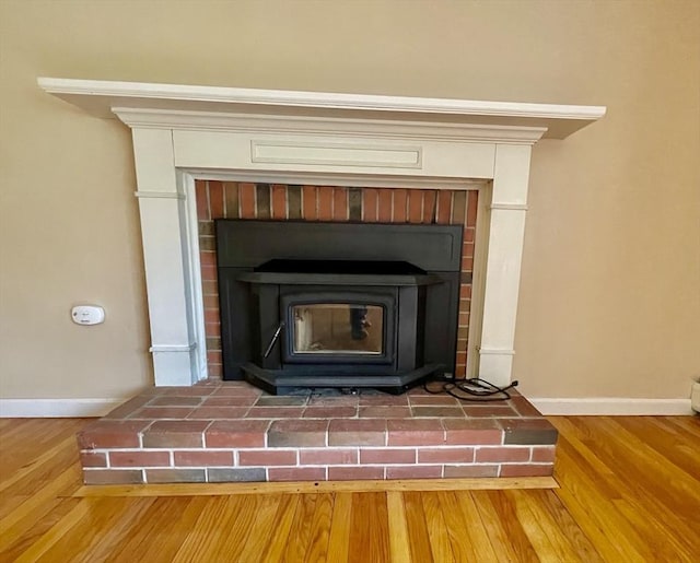 detailed view of baseboards, a wood stove, and wood finished floors