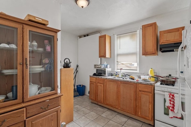 376 Elm St, Fitchburg, MA 01420 - kitchen with stainless steel microwave, gas range gas stove, light tile patterned flooring, under cabinet range hood, and brown cabinetry