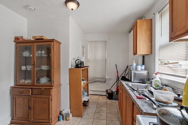 376 Elm St, Fitchburg, MA 01420 - kitchen with stainless steel microwave, brown cabinets, glass insert cabinets, light tile patterned floors, and a baseboard heating unit