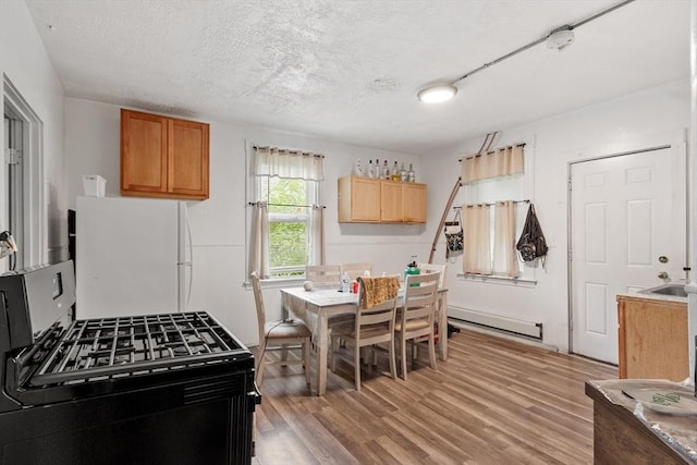 376 Elm St, Fitchburg, MA 01420 - kitchen featuring black range with gas stovetop, freestanding refrigerator, a baseboard heating unit, a textured ceiling, and light wood-type flooring