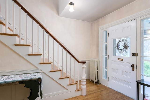 entryway with radiator, wood finished floors, and stairs