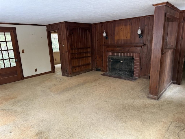 unfurnished living room with wood walls, light carpet, ornamental molding, and a brick fireplace