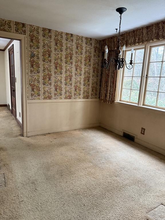 unfurnished dining area featuring light carpet and a notable chandelier