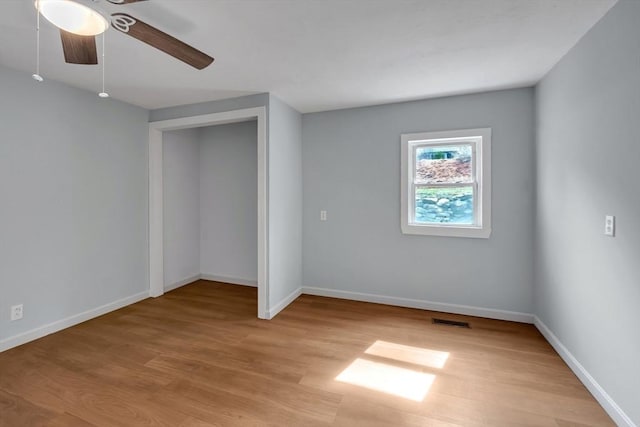 empty room featuring light wood-type flooring, baseboards, ceiling fan, and visible vents